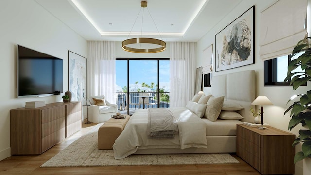 bedroom featuring access to outside, light wood-type flooring, and a raised ceiling