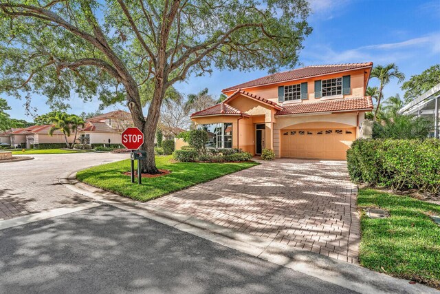 mediterranean / spanish-style home featuring a garage and a front yard