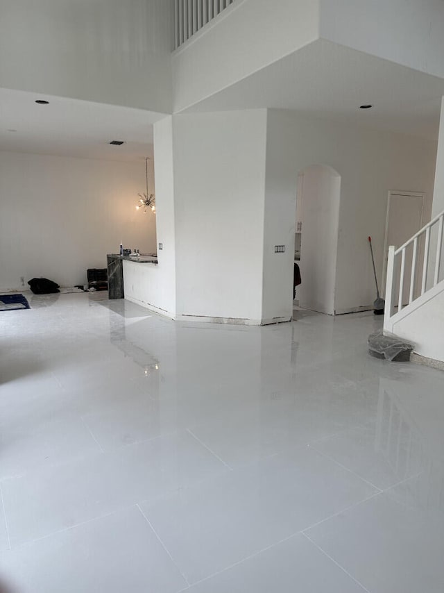 unfurnished room featuring an inviting chandelier and a towering ceiling