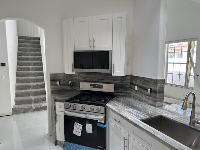 kitchen featuring sink, appliances with stainless steel finishes, tasteful backsplash, light stone countertops, and white cabinets