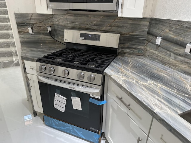 kitchen featuring tasteful backsplash, gas stove, and white cabinets