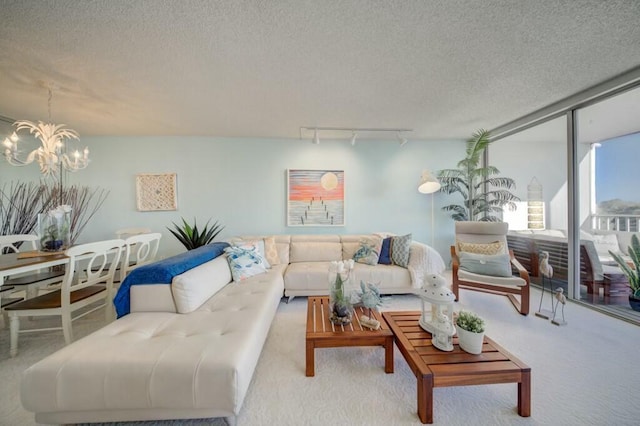 living room featuring light colored carpet, track lighting, a textured ceiling, and a notable chandelier