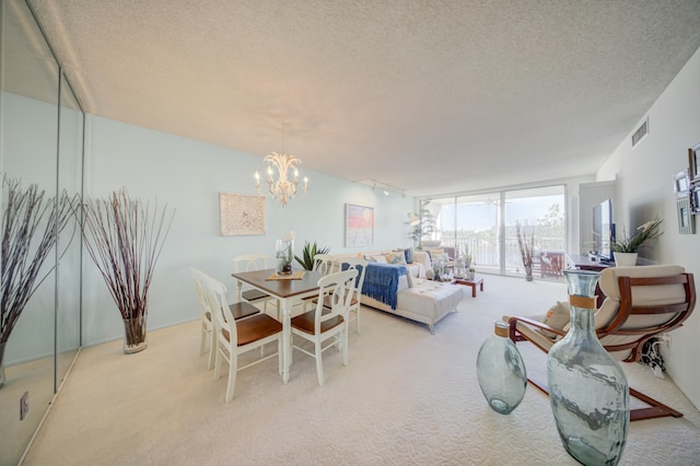 dining room featuring a chandelier, light colored carpet, and a textured ceiling