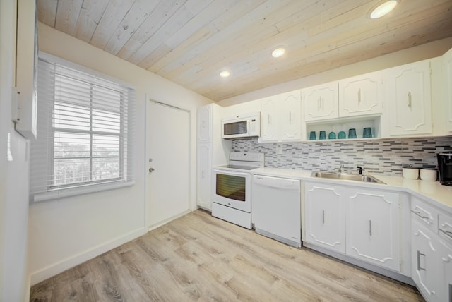 kitchen with tasteful backsplash, white cabinetry, sink, and white appliances