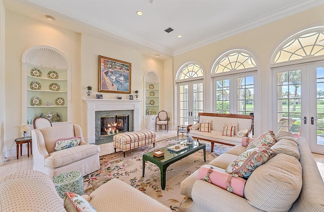 living room featuring french doors, a fireplace, built in features, and crown molding