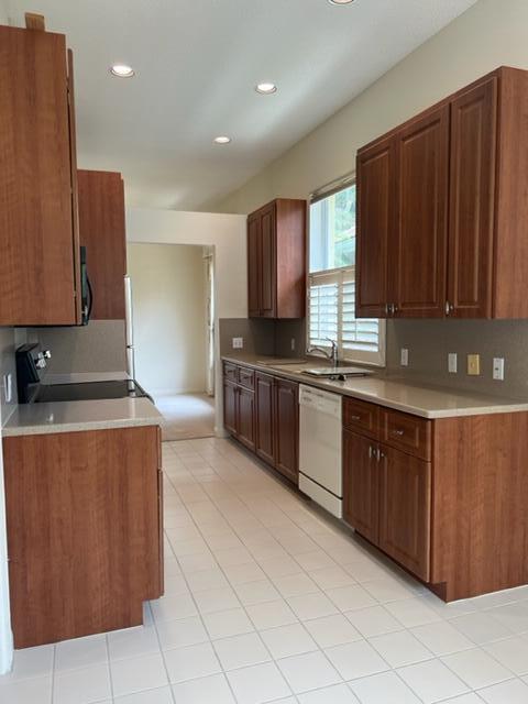 kitchen featuring white dishwasher, sink, decorative backsplash, and stove