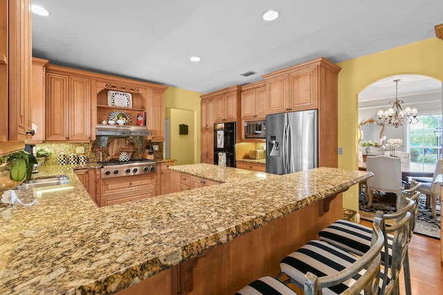 kitchen with appliances with stainless steel finishes, tasteful backsplash, light wood-type flooring, sink, and kitchen peninsula