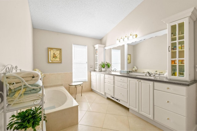 bathroom with tile patterned flooring, a textured ceiling, a tub, vaulted ceiling, and vanity