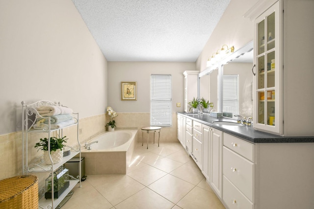 bathroom with vanity, a textured ceiling, tile patterned floors, and tiled bath