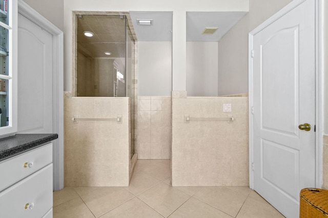 bathroom featuring tile walls, vanity, tile patterned flooring, and tiled shower