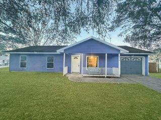 single story home with a garage, a porch, and a front lawn