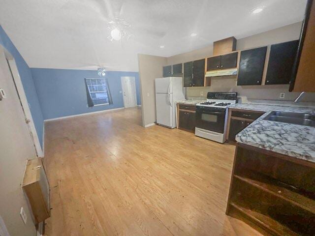 kitchen with light stone counters, white appliances, sink, and light hardwood / wood-style floors