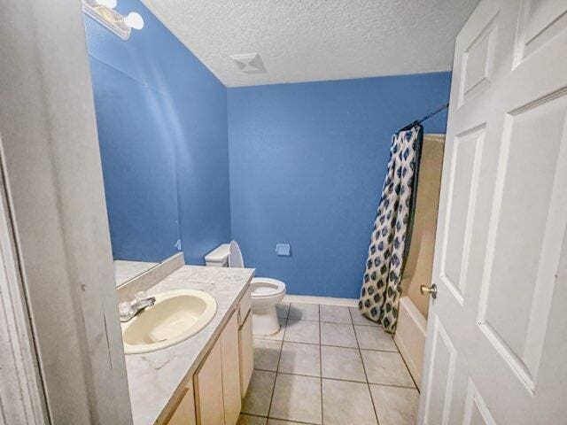 full bathroom with tile patterned flooring, vanity, toilet, shower / bath combo, and a textured ceiling