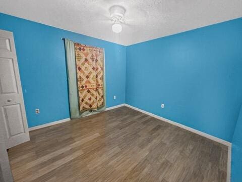 unfurnished bedroom featuring a textured ceiling and dark hardwood / wood-style flooring