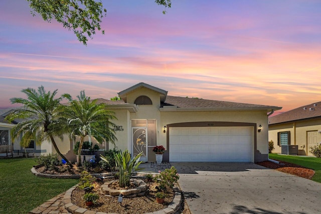 ranch-style home with an attached garage, stucco siding, central AC, and driveway