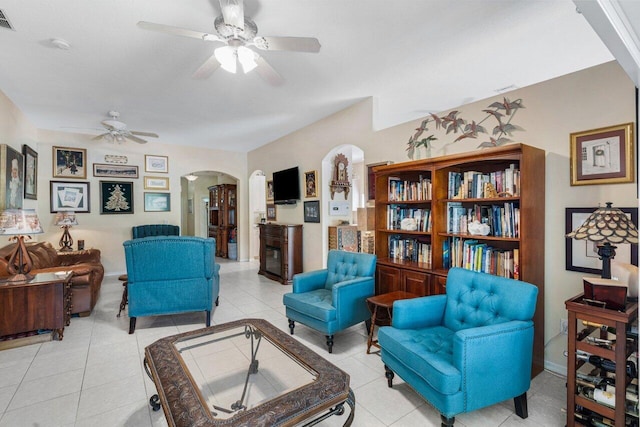 living area featuring a ceiling fan, visible vents, baseboards, arched walkways, and light tile patterned flooring