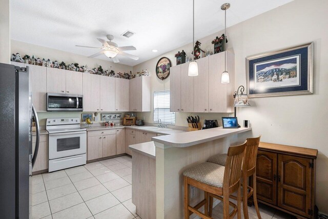 kitchen featuring a ceiling fan, a sink, a peninsula, light countertops, and appliances with stainless steel finishes