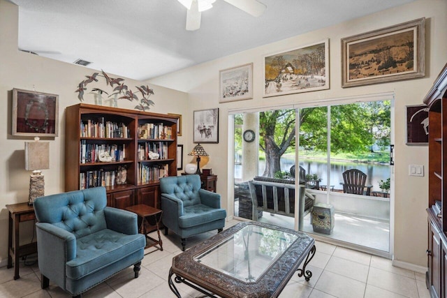 living area featuring a ceiling fan, baseboards, a water view, and light tile patterned floors