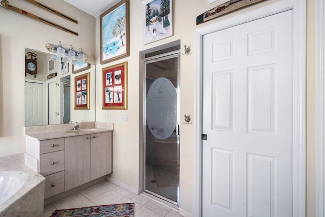 bathroom with a garden tub, a stall shower, baseboards, tile patterned flooring, and vanity
