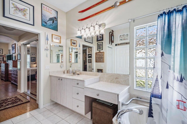 bathroom with ensuite bathroom, tile patterned flooring, vanity, and a tub to relax in