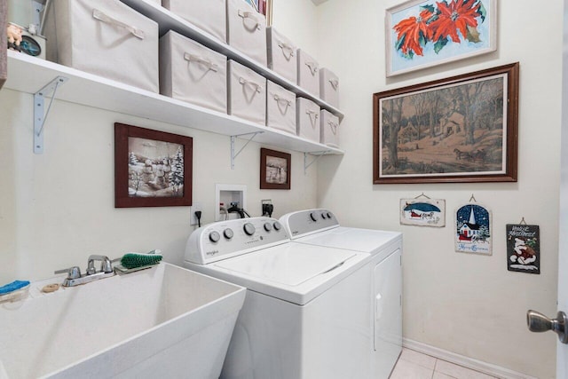 clothes washing area featuring washer and dryer, a sink, laundry area, baseboards, and light tile patterned flooring