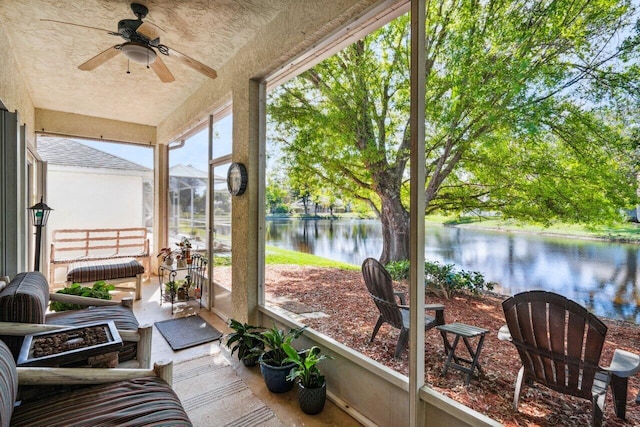 sunroom featuring a water view and a ceiling fan