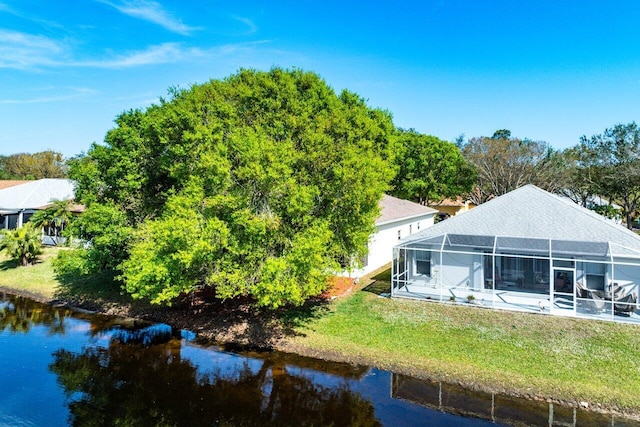 rear view of property with a yard, a water view, and glass enclosure