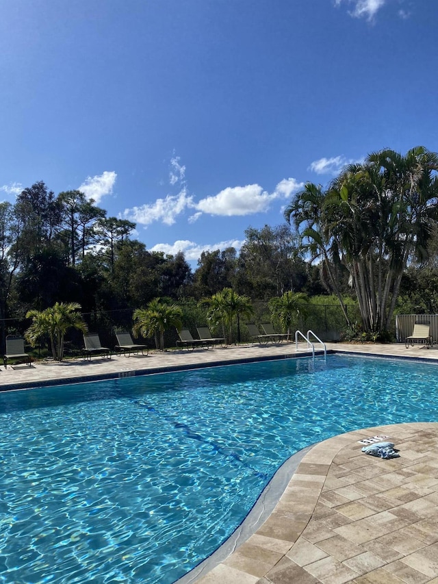 community pool with a patio and fence