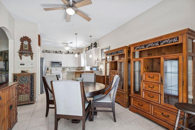 dining area featuring ceiling fan, arched walkways, and light tile patterned floors