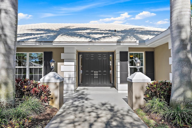 doorway to property featuring roof with shingles and stucco siding