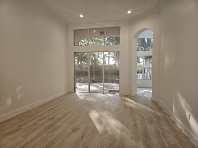 empty room featuring hardwood / wood-style floors, ornamental molding, and a high ceiling