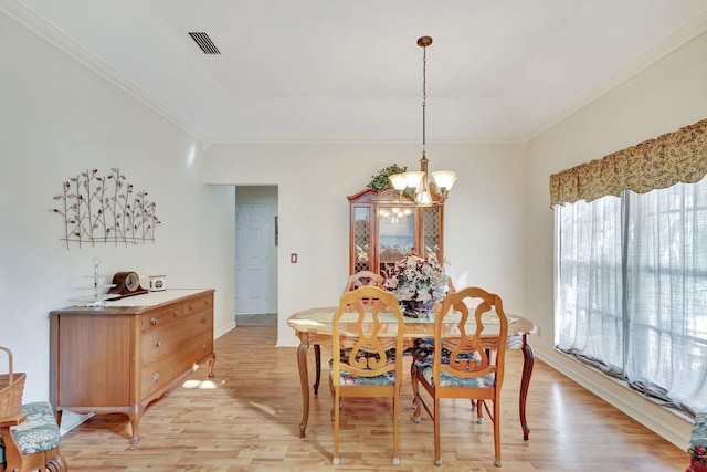 dining area featuring an inviting chandelier, a tray ceiling, and light wood-type flooring