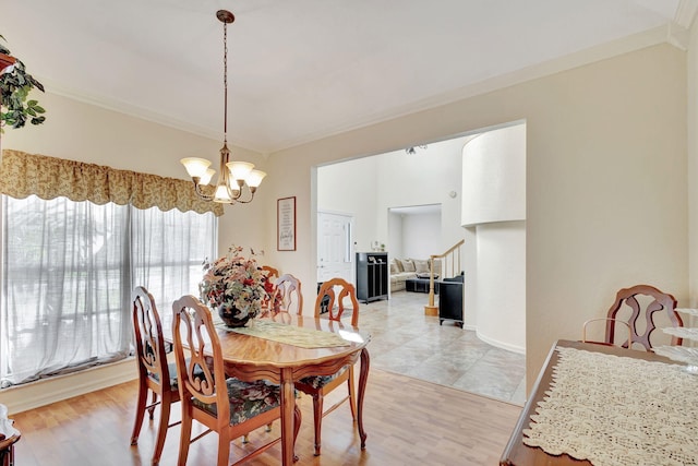 dining room with crown molding, light wood-type flooring, and an inviting chandelier