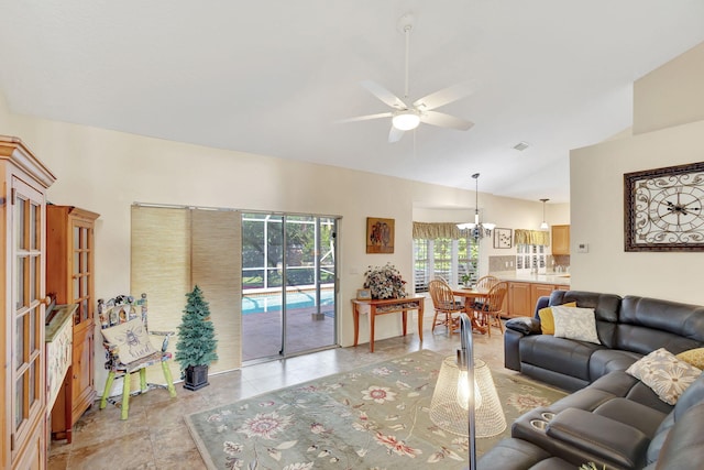 living room with ceiling fan with notable chandelier and vaulted ceiling