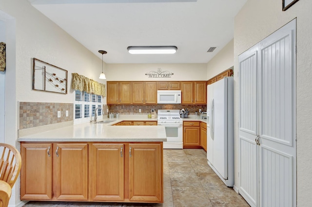 kitchen with sink, kitchen peninsula, pendant lighting, white appliances, and decorative backsplash