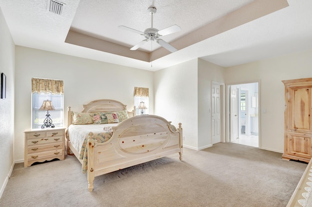 carpeted bedroom featuring ceiling fan, a tray ceiling, and a textured ceiling