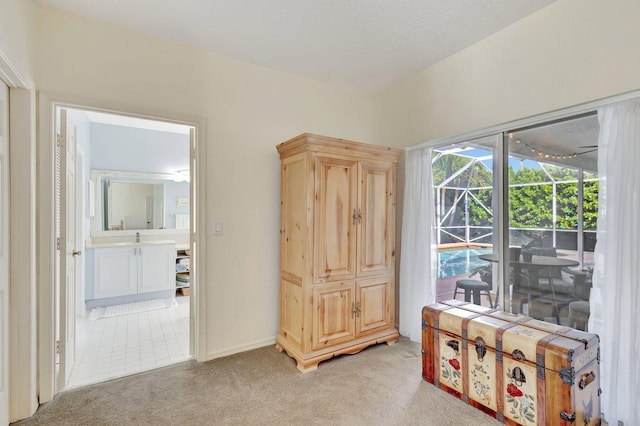 interior space with sink, access to outside, light colored carpet, and ensuite bath