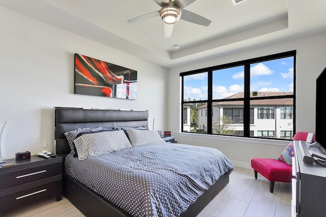 bedroom featuring a raised ceiling and ceiling fan