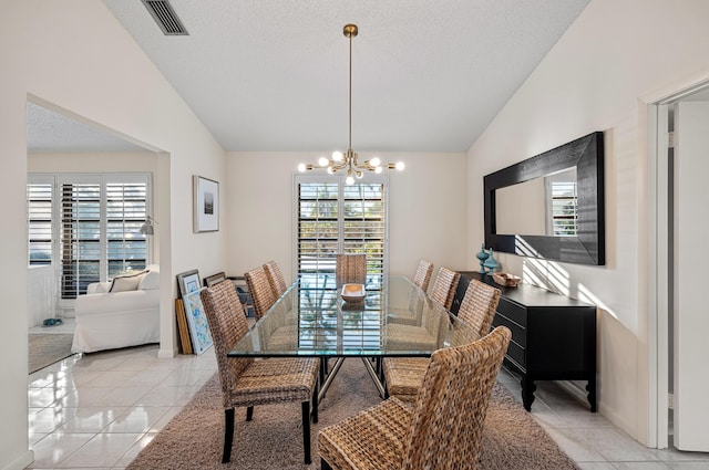 tiled dining space featuring lofted ceiling, a notable chandelier, and a textured ceiling