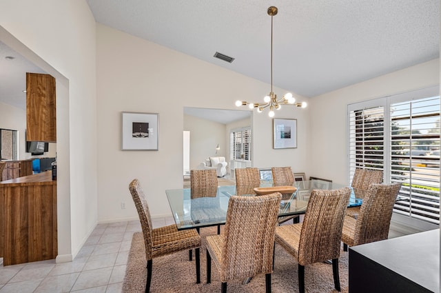 tiled dining space featuring vaulted ceiling, a textured ceiling, and a notable chandelier