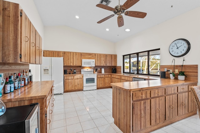 kitchen featuring high vaulted ceiling, light tile patterned floors, appliances with stainless steel finishes, kitchen peninsula, and decorative backsplash