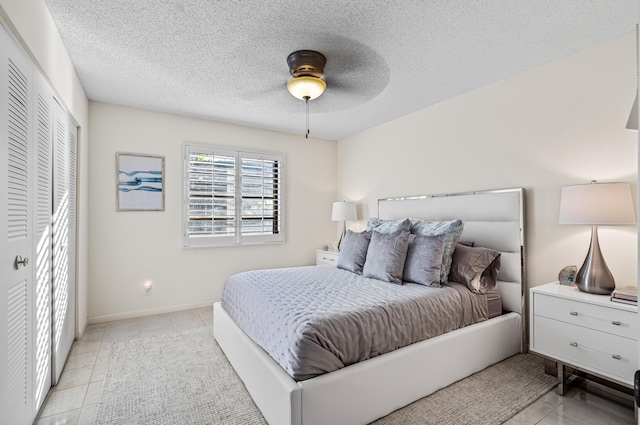 bedroom with ceiling fan, light tile patterned floors, and a textured ceiling