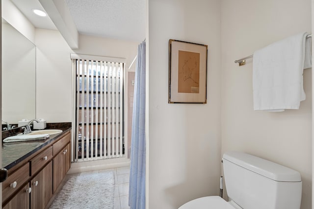 bathroom featuring tile patterned floors, vanity, toilet, and a textured ceiling