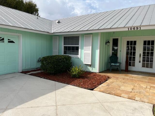 entrance to property featuring french doors, metal roof, a standing seam roof, and an attached garage