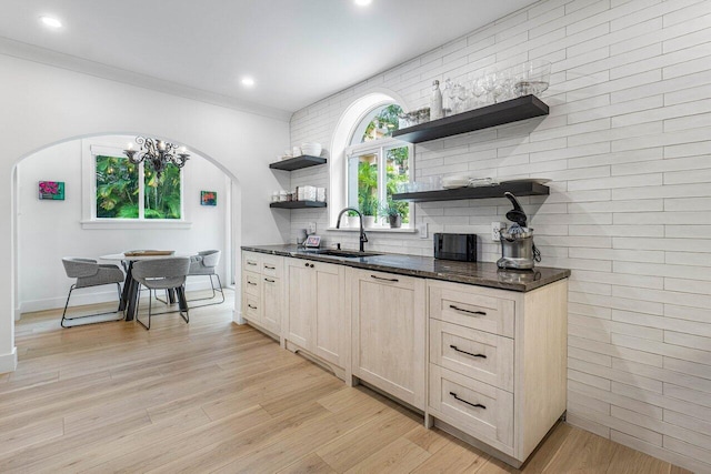 kitchen with light brown cabinetry, sink, crown molding, light hardwood / wood-style flooring, and backsplash