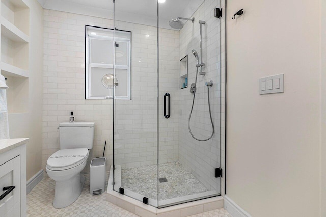 bathroom featuring vanity, a shower with shower door, and toilet