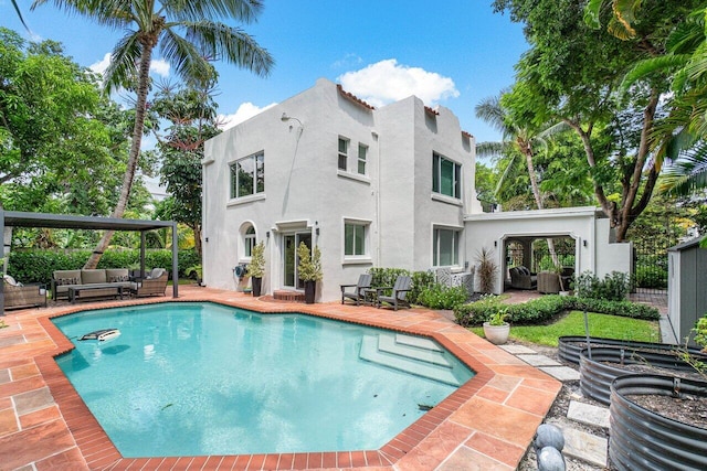 rear view of property featuring an outdoor living space, a patio area, and a fenced in pool