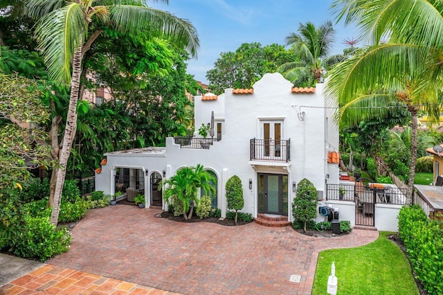 mediterranean / spanish home with french doors and a balcony