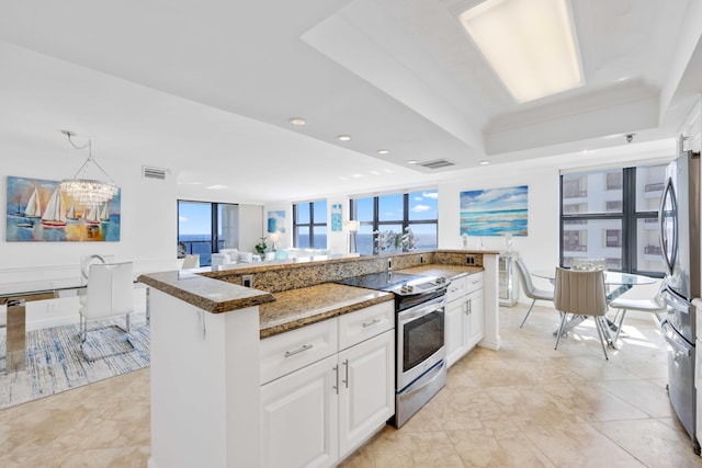 kitchen with white cabinetry, dark stone countertops, stainless steel appliances, a notable chandelier, and a raised ceiling