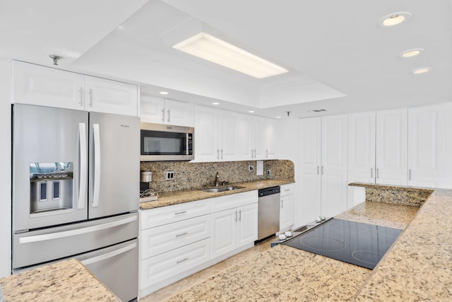 kitchen with stainless steel appliances, light stone countertops, sink, and white cabinets